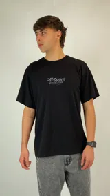Remera negra de corte holgado con cuello redondo y mangas cortas. Presenta un estampado gráfico pequeño en el centro del pecho con la inscripción 'Off-Court'.