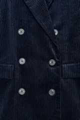 Blazer de pana azul marino con diseño cruzado, cuello solapa, hombreras marcadas y cierre frontal con botones. Cuenta con bolsillos delanteros con solapa y abertura en la espalda.