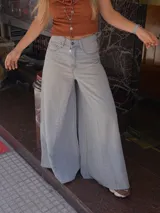 Pantalón de jean celeste de tiro medio con pierna extra ancha y caída fluida, con bolsillos delanteros y traseros, y cierre frontal con cremallera y botón metálico.