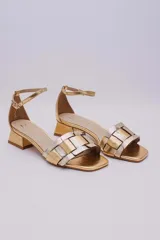 Sandalias bajas doradas con tiras anchas entrecruzadas en dorado y plateado, con pulsera al tobillo y taco cuadrado bajo.