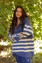 Buzo de lana merino con diseño a rayas horizontales en azul y blanco, cuello alto con cierre frontal y mangas largas.