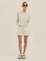 Shorts celestes a rayas verticales, de tiro alto y corte holgado, con pinzas en el frente y detalle de Polonio en cobre.