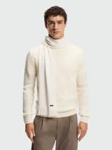Bufanda de punto Raschel color blanco hueso, con diseño liso y terminación en flecos cortos. Incluye una pequeña etiqueta metálica con el logo de la marca.