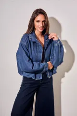 Campera bomber de jean con corte oversize, cierre frontal y cuello alto con botones a presión. Presenta mangas amplias y puños ajustados.