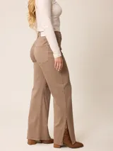 Pantalón jean de tiro alto y corte recto, color marrón chocolate, con aberturas laterales en el ruedo.