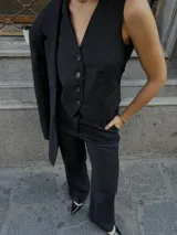 Pantalón de vestir negro con finas rayas verticales, confeccionado en lana. Corte sastrero de tiro alto y pierna ancha.