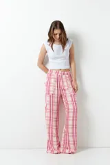 Pantalón de pijama con estampado a cuadros en tonos rosa y blanco, con bolsillos laterales y elástico en la cintura.