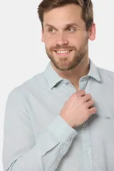 Camisa de manga larga, corte slim fit, color celeste con finas rayas verticales blancas. Presenta cuello camisero y un pequeño logo bordado en el pecho.