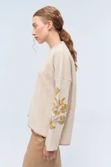 Sweater de punto color gris claro, confeccionado en lambswool. Presenta cuello redondo, combinación de puntos en el frente y bordados florales hechos a mano en las mangas.