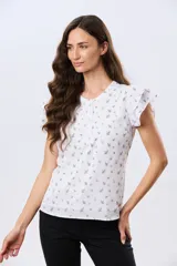 Blusa blanca sin mangas con volados en los hombros, cuello redondo con aberturas y cierre frontal parcial con botones.