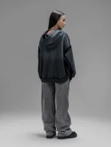 Hoodie oversize de corte crop en color gris oscuro, confeccionado en algodón rústico. Presenta un diseño con costuras expuestas, efecto de desgaste y detalles de roturas en los bordes, incluyendo puños y ruedo.
