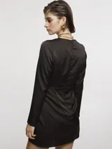 Vestido corto de satén color negro, con escote en V profundo, mangas largas y diseño cruzado en la falda.