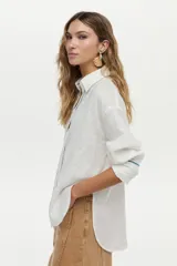 Camisa de lino blanca con detalles de bordado azul en el frente, espalda y puños, mangas largas y corte holgado.