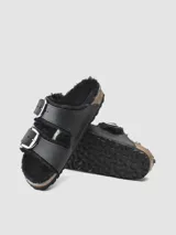 Sandalias Birkenstock Arizona BB Shearling FL color negro, con doble tira ajustable con hebillas plateadas y plantilla anatómica forrada en lana de oveja natural.