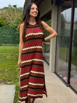 Vestido largo de tejido de punto con patrón en zigzag de rayas en tonos marrón, rojo, negro y beige, sin mangas y con escote redondo.