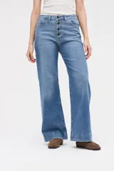 Jean de corte wide leg con tiro medio y cierre frontal con botones a la vista. Presenta un diseño holgado desde la cadera hasta el bajo con pierna ancha.