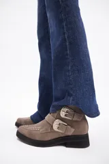 Botín de cuero vacuno color marrón, con punta fina y detalle de tachas metálicas en la parte superior. Presenta una suela de plataforma plana de color negro.