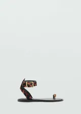Sandalia plana con diseño de dedo, confeccionada en piel bovina con pelo y estampado de leopardo. Cuenta con una tira tobillera ajustable mediante hebilla metálica dorada y un detalle metálico en el anillo del dedo.