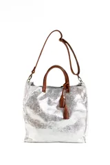 Bolso tipo shopper de cuero con acabado metalizado plateado, asas cortas y correa larga ajustable en color marrón. Incluye detalle de borlas decorativas en el frente.