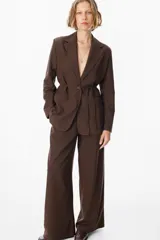 Blazer de corte sastrero en color marrón chocolate, con solapas clásicas, cierre frontal de un botón y bolsillos laterales con solapa.