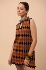 Vestido corto sin mangas con estampado de rombos en azul, rojo y amarillo. Tiene escote con forma de gota y terminación en picos.