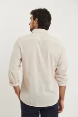 Camisa de manga larga confeccionada en una mezcla de algodón y lino, con cuello abotonado, cierre frontal de botones y un bolsillo en el pecho.