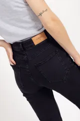 Jean oxford de tiro alto en color negro, confeccionado en denim con elasticidad. Presenta un corte ajustado en la parte superior y acampanado desde la rodilla hacia abajo, con cierre frontal y bolsillos.