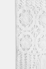 Falda midi semitransparente de punto crochet color blanco, con cintura elástica y bajo asimétrico con flecos.