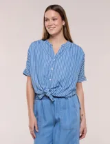 Blusa de silueta amplia de lyocell color azul con diseño de rayas verticales blancas. Cuenta con cuello mao abierto, abotonadura frontal, mangas cortas caídas y lazos en el ruedo para anudar al frente.