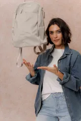 Mochila compacta de color beige, con compartimento principal con cierre, bolsillos laterales y bolsillo frontal con cierre oculto. Cuenta con correas regulables y acolchonadas y asa superior.