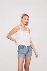 Musculosa blanca con breteles finos y detalles de puntilla.