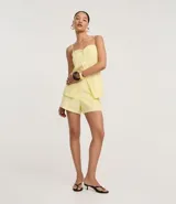 Short de sastrería color amarillo claro, de tiro alto con cintura elástica y cierre tradicional. Presenta frisos verticales en la parte delantera.