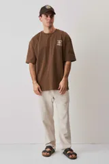 Remera oversize marrón de corte relajado, con cuello redondo y diseño estampado en el pecho y la espalda.
