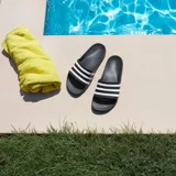 Ojotas Adidas Adilette Aqua de color negro con tres bandas blancas en el empeine, diseño de una sola pieza moldeada.