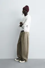Pantalón de corte baggy fit confeccionado en tejido de algodón con textura y efecto lavado. Presenta diseño de cinco bolsillos, cierre frontal con cremallera y botón.