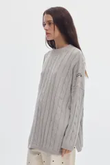 Buzo negro de tejido de ochos, con cuello redondo y diseño oversized de corte largo y amplio con tajos laterales.