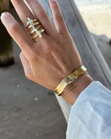 Pulsera tipo esclava abierta con diseño rústico y acabado irregular, fabricada en bronce y alpaca.