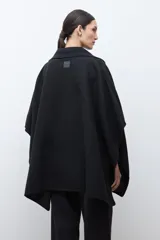 Capa negra con solapa y cuello tejido, de corte amplio y sin mangas.