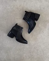 Botines negros de cuero con taco cuadrado y detalle de tachas doradas en el tobillo.