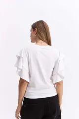 Remera negra de algodón con mangas cortas que presentan volados dobles, aportando volumen y movimiento a la prenda.