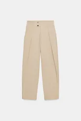 Pantalón de tiro bajo con pinzas delanteras, bolsillos frontales y bolsillos de plastrón con solapa en la parte trasera. Presenta una pernera ancha y bajo con botones a presión para ajuste.