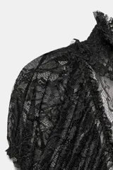 Top negro de encaje semitransparente, con cuello alto, manga corta y diseño drapeado con frunces en el centro. Presenta acabado con volantes en el bajo.