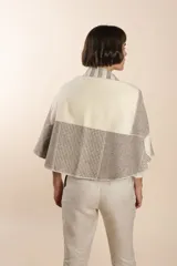Chaleco sin mangas de tejido de lana fina sin teñir, con diseño circular y bloques de color beige y marrón. Presenta un cuello amplio y solapa que permite usarlo como chaleco largo o capa corta.