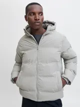 Campera puffer color gris claro, con capucha, cierre frontal con cremallera y diseño acolchado. Cuenta con puños internos acanalados y acabado resistente al agua.