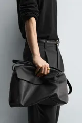 Bolso tipo bandolera de piel con acabado grabado, diseño rectangular con solapa frontal y cierre magnético. Cuenta con un asa de hombro ajustable y compartimento interior con cierre de cremallera.
