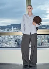 Camisa celeste a rayas verticales blancas, de corte recto, manga larga con puños abotonados, cuello camisero y bolsillo de parche en el pecho.