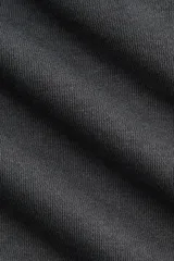 Buzo en tejido liviano color gris oscuro, con cuello camisero, tapeta de botones, hombros caídos y puños acanalados.