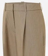 Pantalón de sastrería de crepé color marrón, de corte carrot, con pliegues delanteros, pinzas, bolsillos laterales y cierre frontal.