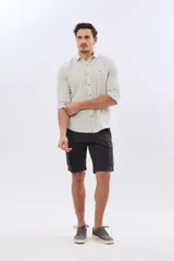 Bermuda cargo color azul marino, de gabardina con bolsillos laterales con solapa en las piernas y presillas para cinturón. Incluye cinturón de lona trenzada oscura con detalles en cuero sintético y hebilla metálica.