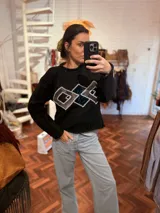 Sweater negro de tejido flexible con apliques geométricos metálicos bordados a mano.